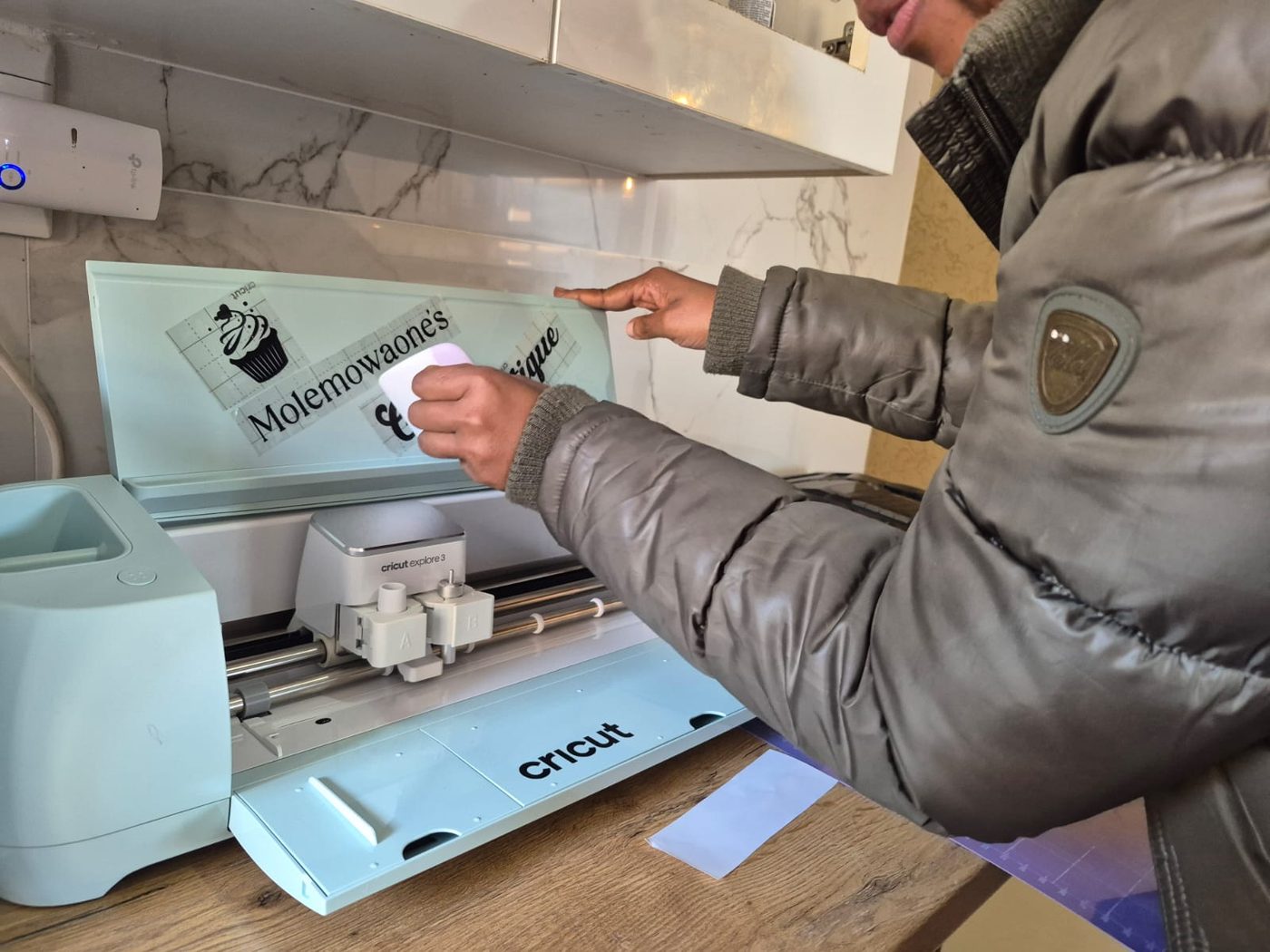 A student cutting a custom cake topper design on a Cricut machine during a class